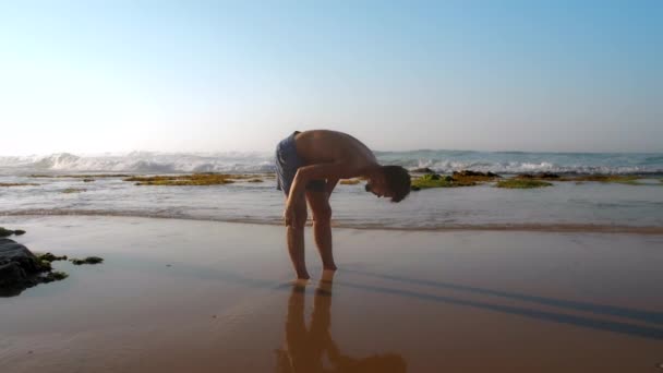 Experienced athlete stands in wet sand reflecting silhouette — Stock Video