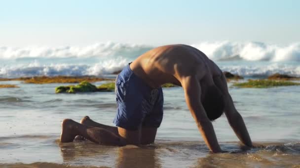 Knappe man doet yoga oefeningen in de buurt van eindeloze oceaan — Stockvideo