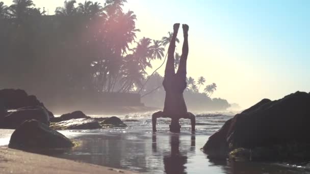 Sporty man silhouette balances on hands and head slow — Stock Video