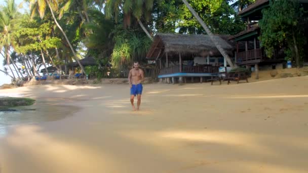 Exciting athlete in blue shorts runs along yellow coastline — Stock Video