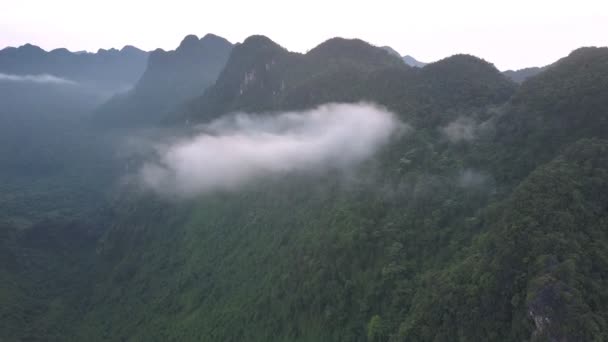 Små vita moln hänger nära höga gröna bergstoppar — Stockvideo