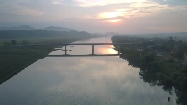 Flycam se move a partir de alta longa ponte sobre rio largo ao pôr do sol — Vídeo de Stock