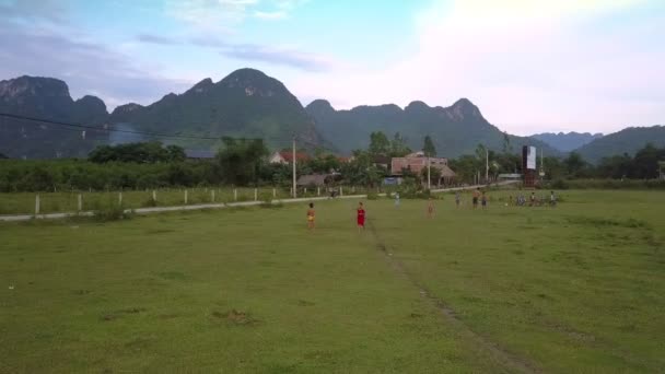 Kinderen spelen voetbal op groene veld tegen hoge bergen — Stockvideo
