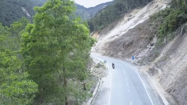 Motorrijder rijdt langs asfalt weg gelegen in ravijn — Stockvideo