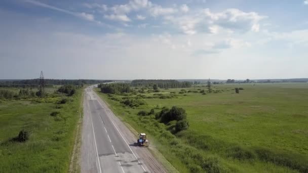 Aerial traktor kör längs väg gräsklippning på vägkanten — Stockvideo