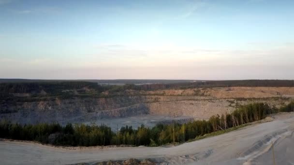 Immense carrière minière grise contre silhouette de petite ville — Video