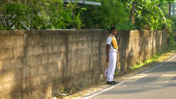 Sinhálský školák se pomalu tyčí na šedé asfaltové silnici — Stock video