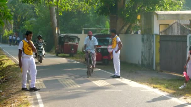 Anak sekolah berseragam kuning putih berdiri di tepi persimpangan — Stok Video