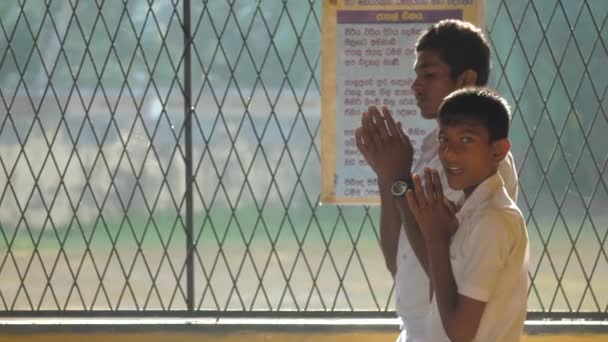 Sonrientes amigos de la escuela en uniforme blanco rezan en clase — Vídeos de Stock