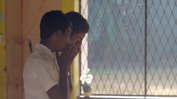 Sinhalese schoolboys pray against large school window — Stock Video