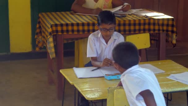 Colegiales cingaleses en uniformes se sientan en escritorio de madera — Vídeos de Stock