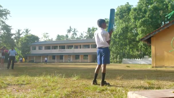 Молодой сингальский школьник держит голубую биту для крикета — стоковое видео