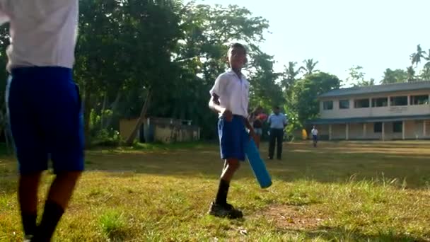 Menino ativo com bastão de críquete azul joga bola para colega de escola — Vídeo de Stock