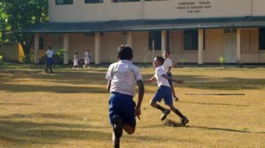 Sinhalese okul çocukları güneşle aydınlatılmış oyun alanında koşmak