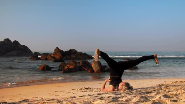 Barefoot young woman in black tracksuit does yoga exercises — Stock Video