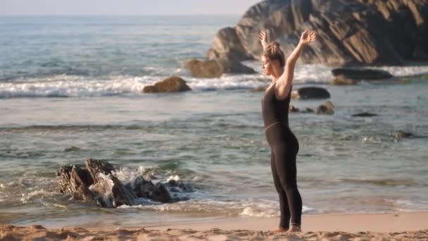 Όμορφη μαλλιά κυρία κάνει ασκήσεις τέντωμα στην παραλία του ωκεανού — Αρχείο Βίντεο
