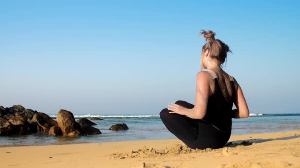 Mädchen ändert Yogapositionen am Strand gegen blauen Ozean