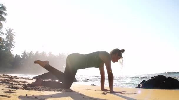 Senhora pratica ioga deixando sombra na praia de areia amarela — Vídeo de Stock