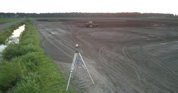 Teodolito y tractor arados campo fértil vista superior del suelo — Vídeo de stock