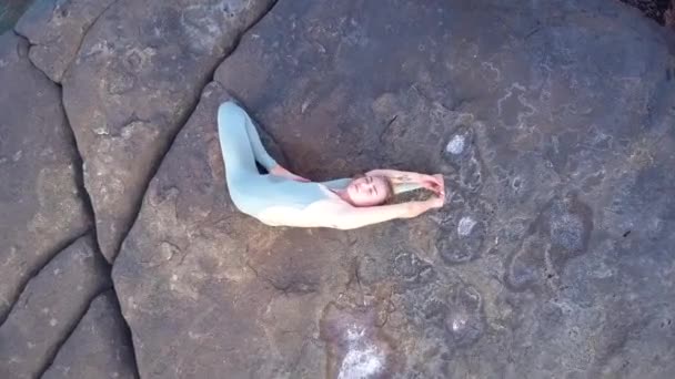 Junge schlanke Frau dehnt Körper beim Pilates auf Stein — Stockvideo