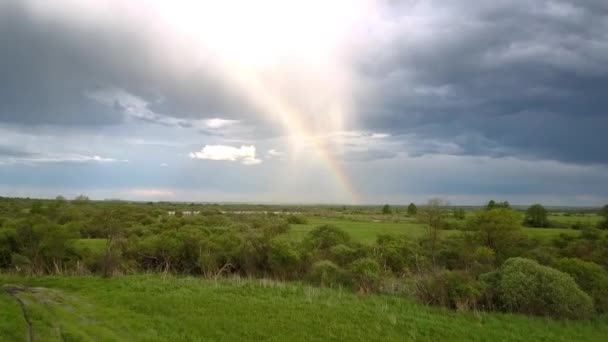 Malerischer Regenbogen über grüne Wiese mit Seenobersicht — Stockvideo