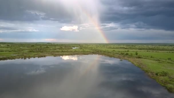 Чудова веселка і блакитні хмари, відображені в спокійному озері — стокове відео
