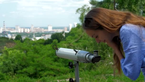 Signora in camicia guarda gli edifici attraverso il telescopio — Video Stock