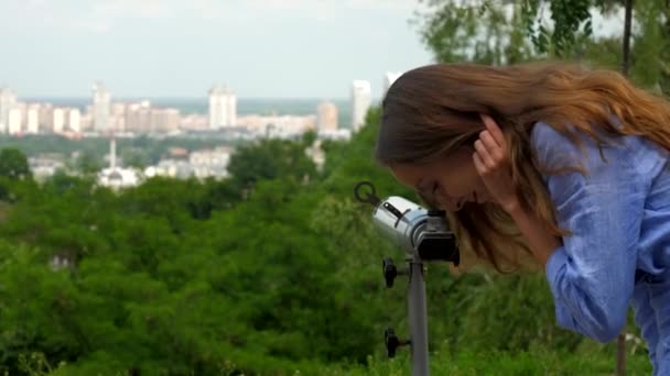 Usměvavá dívka obdivuje cityscate, jak se dívá do šedého dalekohledu — Stock video