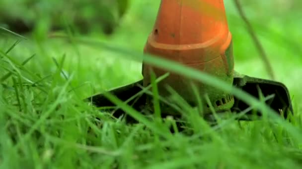 Современный оранжевый триммер с черной деталью косит траву — стоковое видео