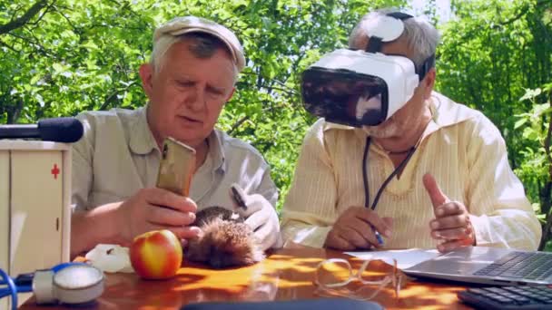 Aged man in steriele handschoen houdt smartphone over egel — Stockvideo