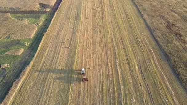 Quadratische Ballenpresse aus der Vogelperspektive arbeitet auf abgeerntetem Feld — Stockvideo