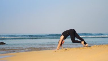 eşofmanlı kız okyanus sahilinde pilates egzersizleri yapar