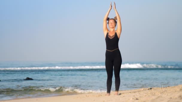 Fair haired woman practices breathing yoga on ocean beach — Stock Video