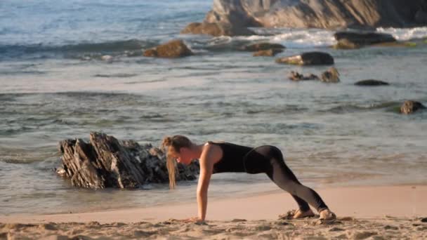 Femme avec des petits pains espace ne pose yoga cobra sur la plage de sable — Video