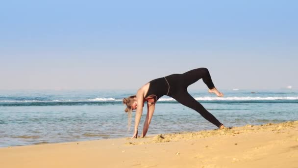 Dame en survêtement noir pratique posture de yoga avancée — Video