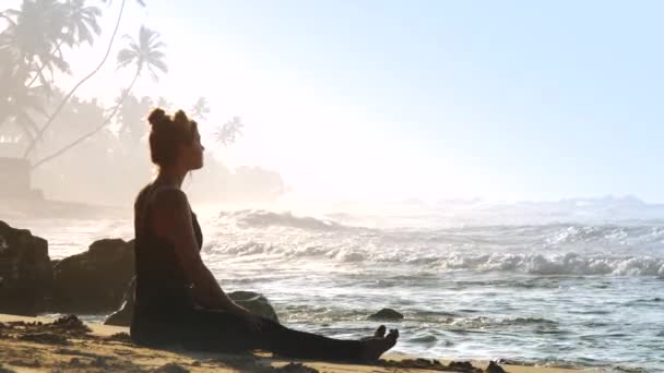 Mujer con bollos espaciales medita en la playa contra el paisaje — Vídeos de Stock
