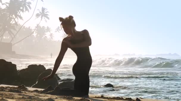 Dame aux cheveux blonds en survêtement noir fait du yoga matinal — Video