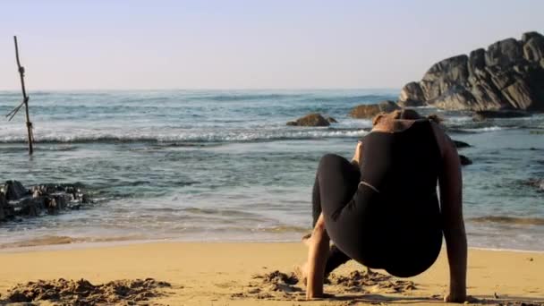 Fille en survêtement noir médite dans yoga pose de huit angles — Video