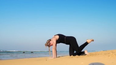 genç kadın okyanusta yoga poz bacak ve el yükseltir