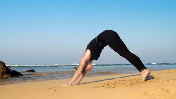 Pieds nus fille en survêtement change de position sur la plage de sable — Video