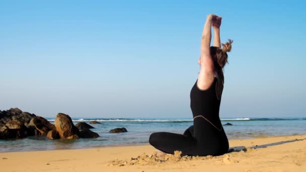 Lady sträcker sig tillbaka öva yoga övningar mot havet — Stockvideo