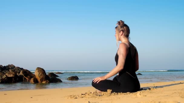 Sportos lány melegítőben meditál a sárga homokos tengerpart — Stock videók