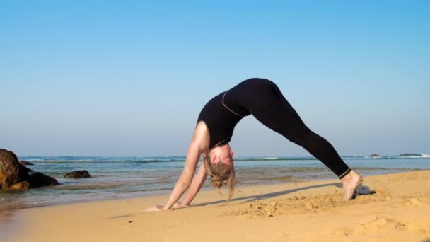 Bella dama equilibra en manos y piernas practicando yoga — Vídeo de stock