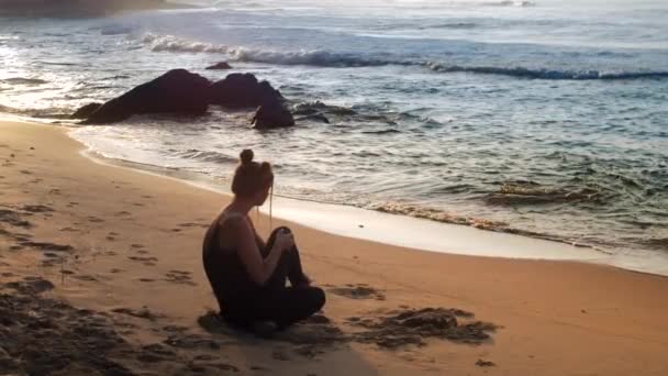 Passionnante dame en survêtement noir se trouve sur la plage de sable de l'océan — Video