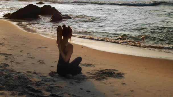 Леди практикует йогу Коровье Лицо упражнения на пляже океана — стоковое видео