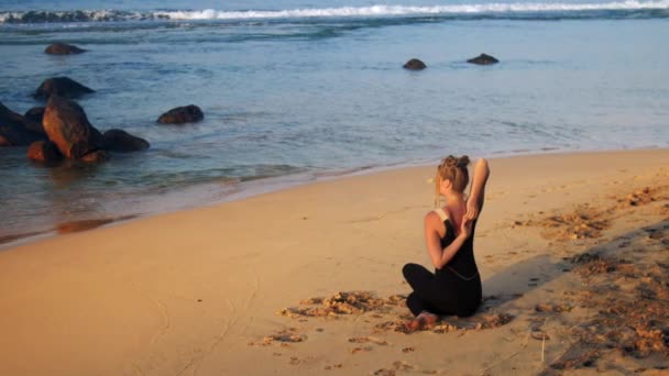 Enorm dam i svart träningsoverall sitter i yoga pose — Stockvideo