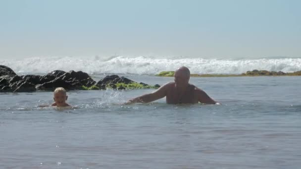 Criança feliz brinca com o pai nadando no oceano azul câmera lenta — Vídeo de Stock