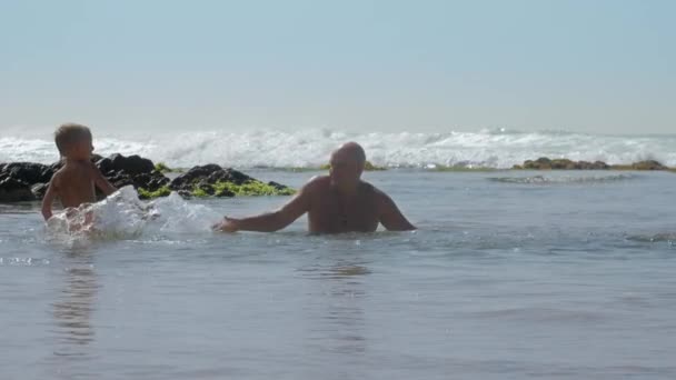 Pequeño niño salpica agua en feliz papá en el mar cámara lenta — Vídeos de Stock