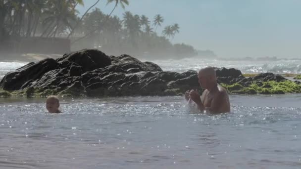 Père passe du temps avec garçon dans l'océan calme près de vieilles pierres — Video