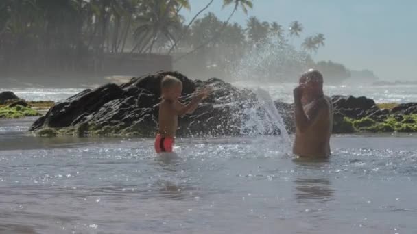 パパと男の子は静かな海で水を飛び散らす楽しみを持っています — ストック動画